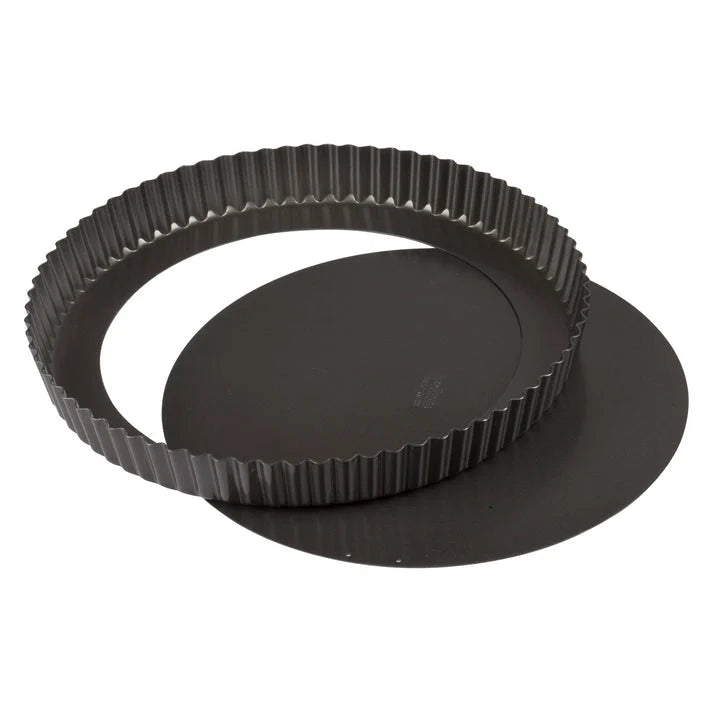 Dark round quiche pan with fluted sides, shown with its removable base separated